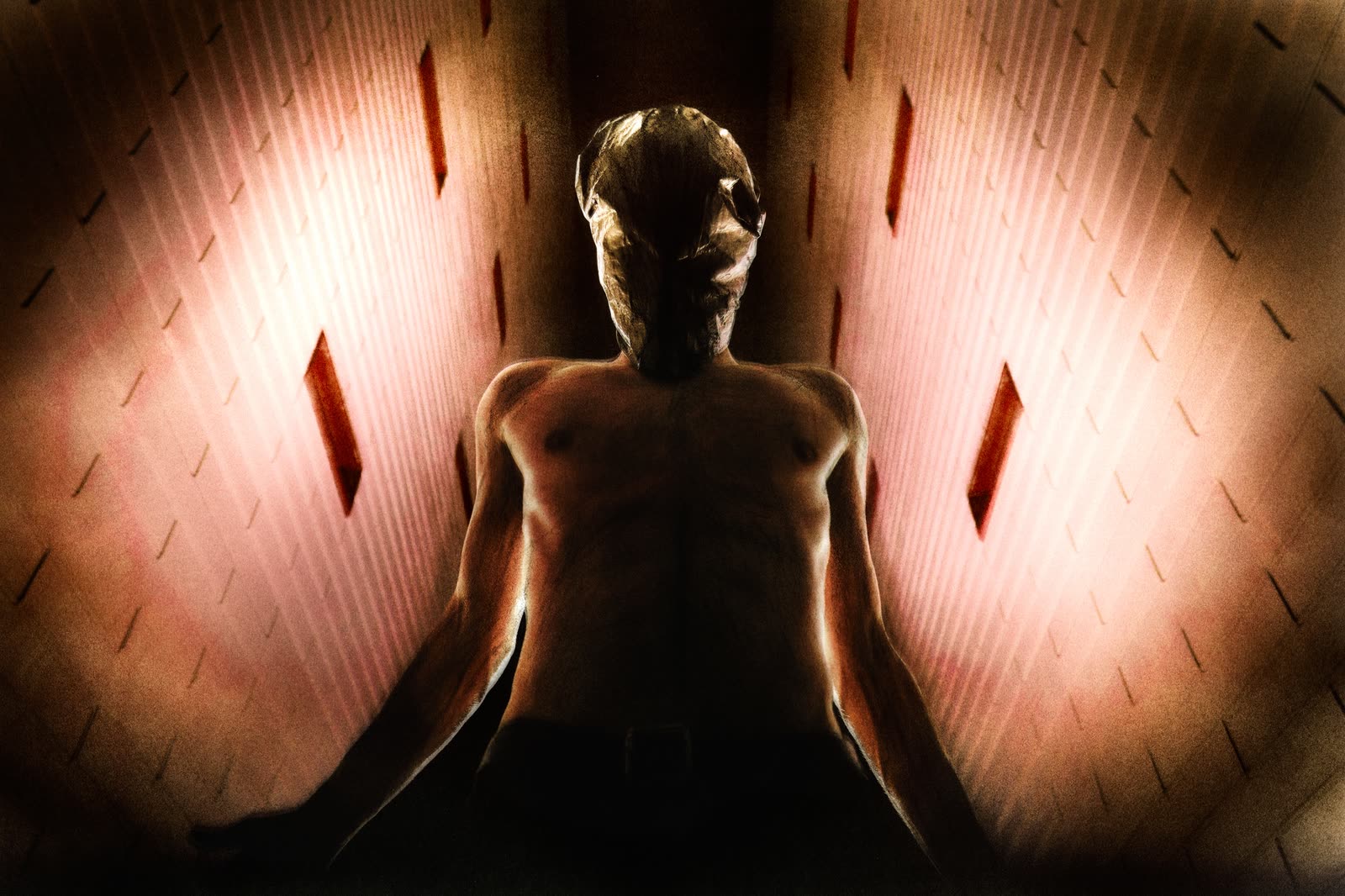Figure in a sodium-lit brick corridor, arms outstretched.